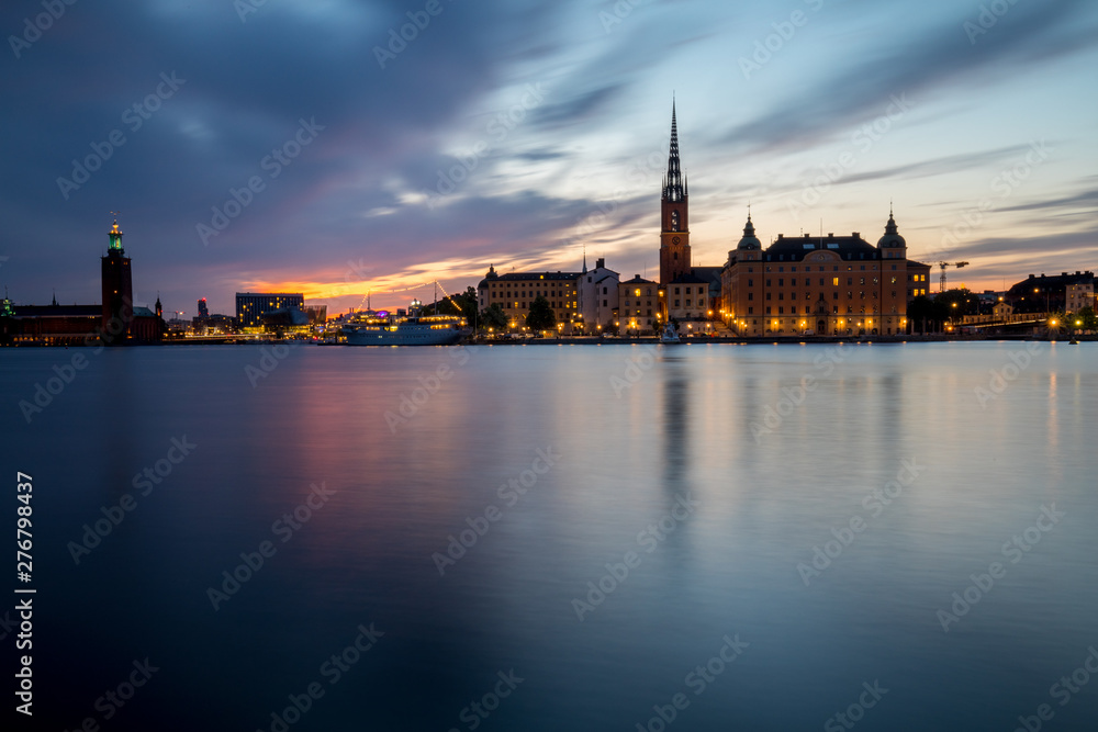 Stockholm, panoramic view over the old town and city hall at sunset with city light and boat