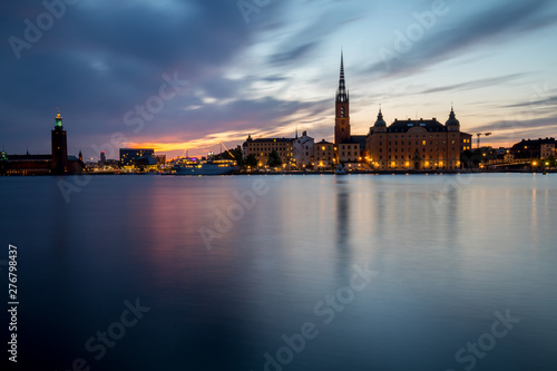 Stockholm, panoramic view over the old town and city hall at sunset with city light and boat