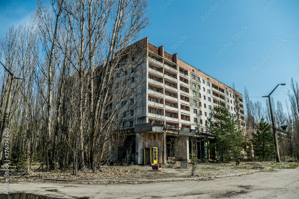 Street of the abandoned ghost town Pripyat. Overgrown trees and collapsing houses in the exclusion zone of the Chernobyl nuclear disaster