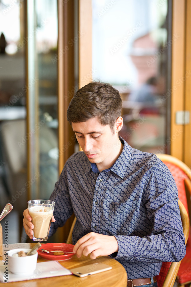 man sitting in cafe and drinking coffee, large latte in man's hands man sitting in cafe and drinking coffee, large latte in man's hands