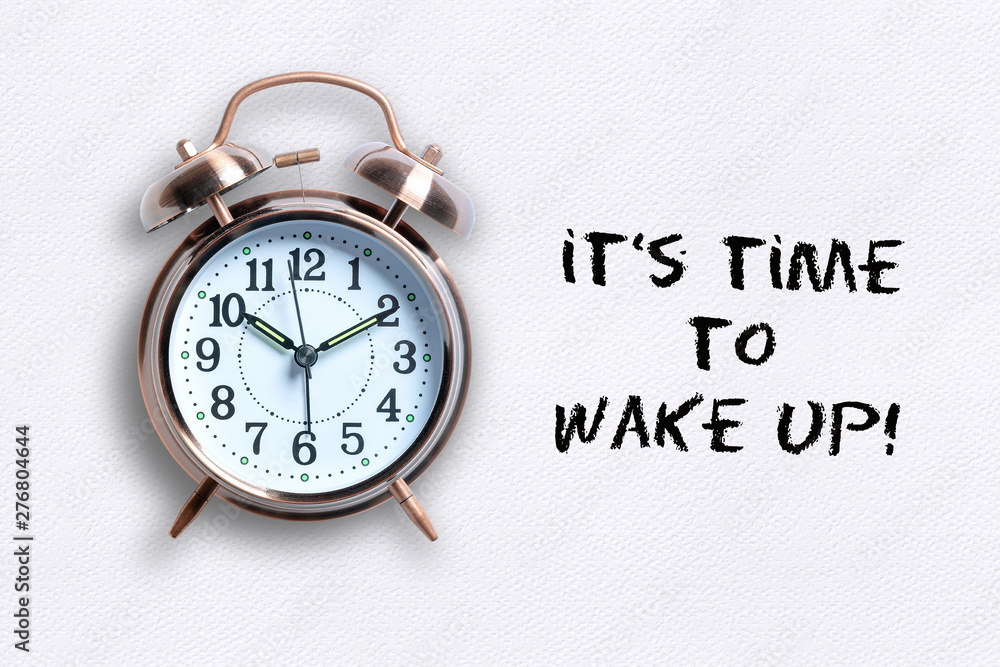 classical copper colored alarm clock with bells in a Wake Up concept on paper background with text classical copper colored alarm clock with bells in a Wake Up concept on paper background with text