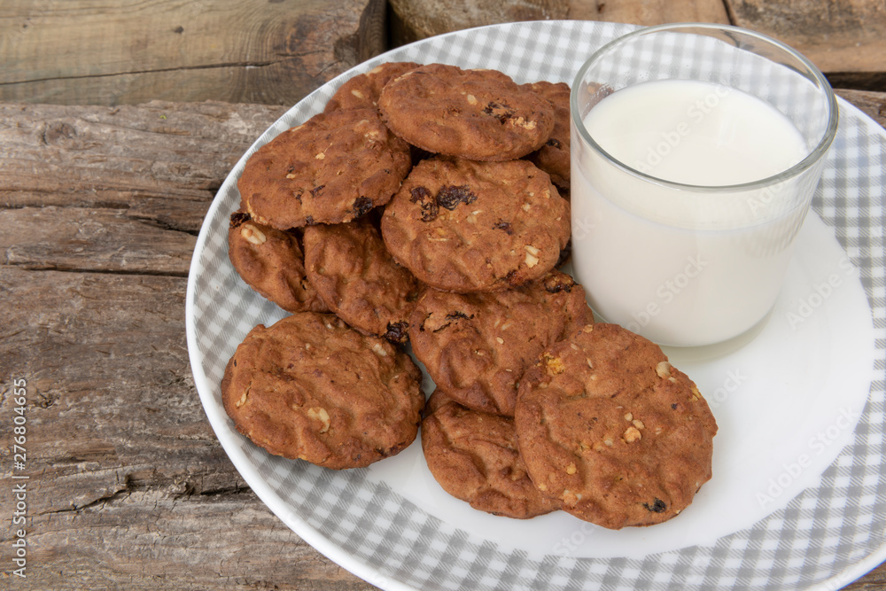 Un vaso de leche y galletas integrales con muesli y pasas.