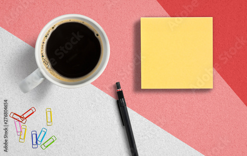 coffee cup with sticky notes, pen and paper clips on paper background
