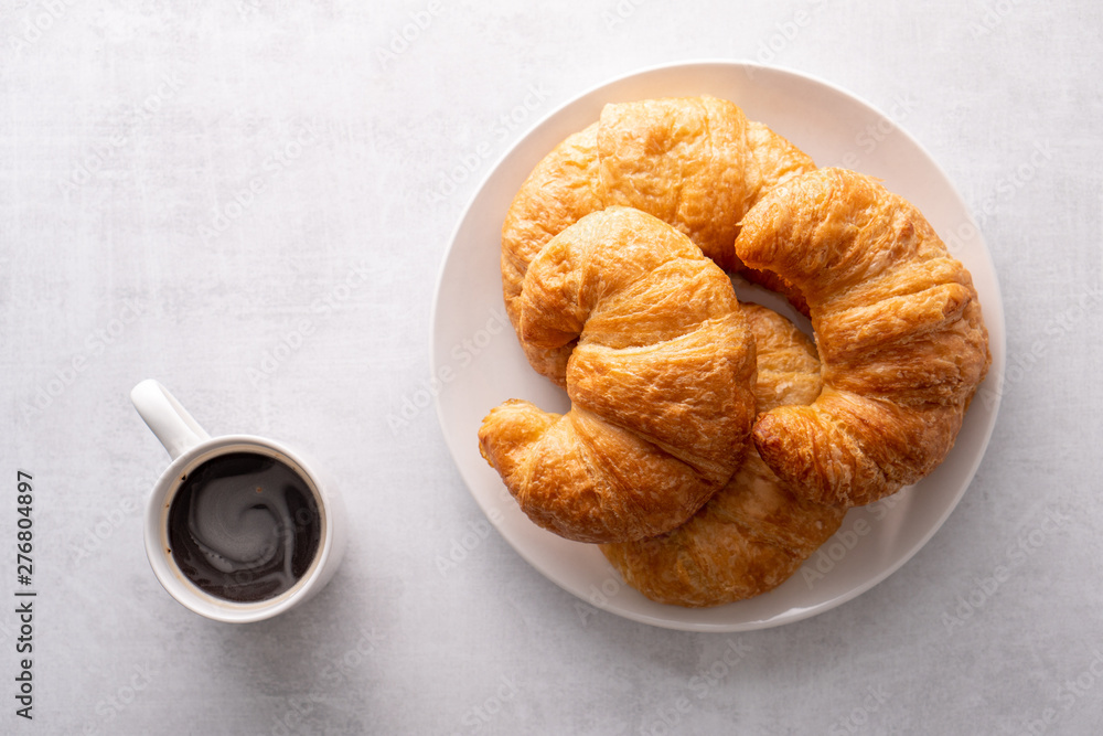 Warm crispy flaky croissant roll on white plate and distressed table. Warm crispy flaky croissant roll on white plate and distressed table.