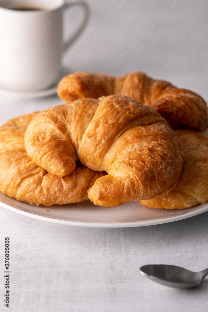 Warm crispy flaky croissant roll on white plate and distressed table. Warm crispy flaky croissant roll on white plate and distressed table.