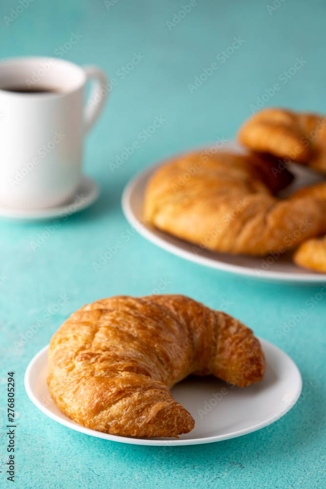 Warm crispy flaky croissant roll on white plate and distressed table. Warm crispy flaky croissant roll on white plate and distressed table.