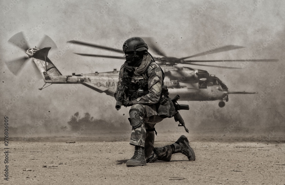 Military soldier between dust in front of helicopter in battle field - obrazy, fototapety, plakaty 