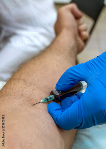 hands of a medical worker in blue gloves take blood from a vein for tests