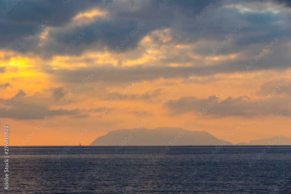 Picturesque sunset over Tyrrhenian Sea in Milazzo town, Sicily, Italy. Aeolian Islands (Italian: Isole Eolie), volcanic archipelago on the north of Sicily on the background