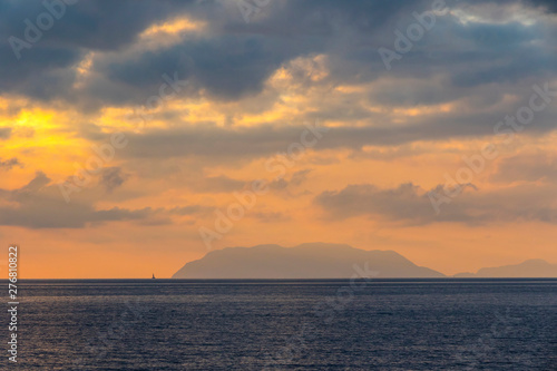 Picturesque sunset over Tyrrhenian Sea in Milazzo town, Sicily, Italy. Aeolian Islands (Italian: Isole Eolie), volcanic archipelago on the north of Sicily on the background