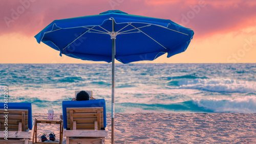 Man reads book by the ocean on Singer Island  Florida beach during a dramatic sunrise