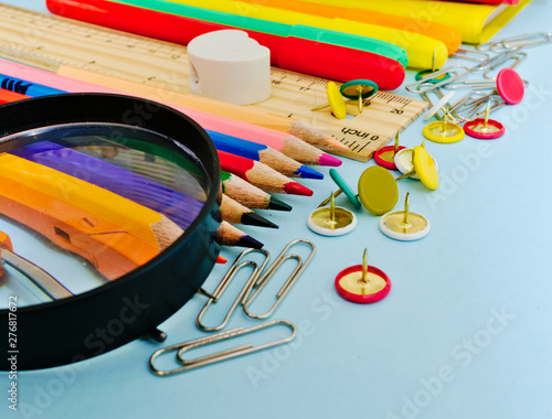 Colorful  school suplies against light blue background with copy space. Back to school concept, diagonal view. photo