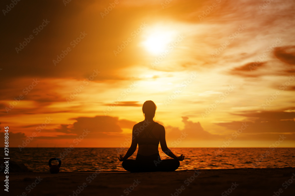 woman practicing yoga during surrealistic sunset at the seaside. healthy concept and workout.