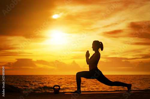 woman practicing yoga during surrealistic sunset at the seaside. healthy concept and workout.
