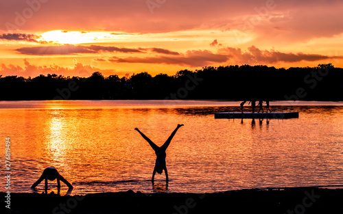 People are having fun in a lake under sunset 