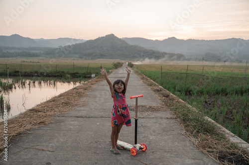 portrait of happy young kid ride her scooter outdoor photo