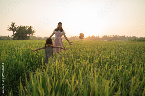 happy asian mother and kid walking in rice field in summer