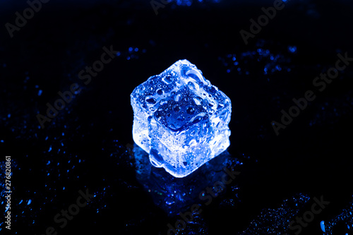 Blue ice cubes on black wet table.