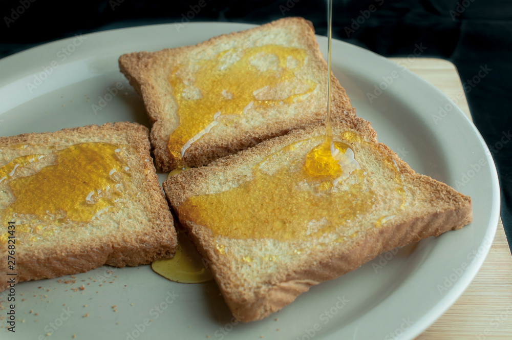 Toast with honey on top on a wooden cutting board Toast with honey on top on a wooden cutting board