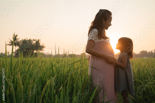beautiful pregnant asian woman with daughter playing on her tummy in summer outdoor © Odua Images