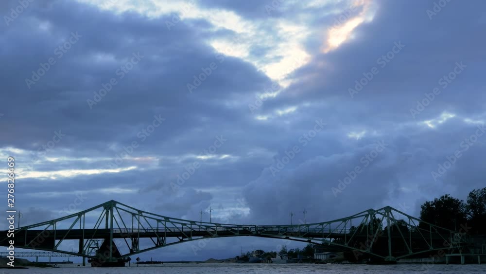 Beautiful fast moving dark gray rain clouds over the Oskara Kalpaka swing bridge in Liepaja city in evening, wide shot Beautiful fast moving dark gray rain clouds over the Oskara Kalpaka swing bridge in Liepaja city in evening, wide shot