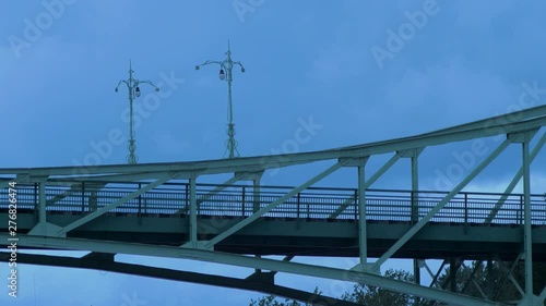 Beautiful fast moving dark gray rain clouds over the Oskara Kalpaka swing bridge in Liepaja city in evening, medium shot photo