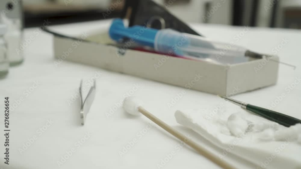 Closeup of laboratory tools on table - tweezers, cotton wool, paint brush and injection with needle Closeup of laboratory tools on table - tweezers, cotton wool, paint brush and injection with needle