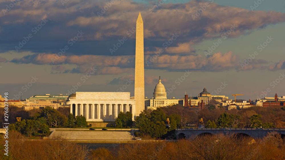 Washington DC panorama with famous landmarks during cloudy winter sunset. Lincoln Memorial, Washington monuments and United States Capitol in city skyline.