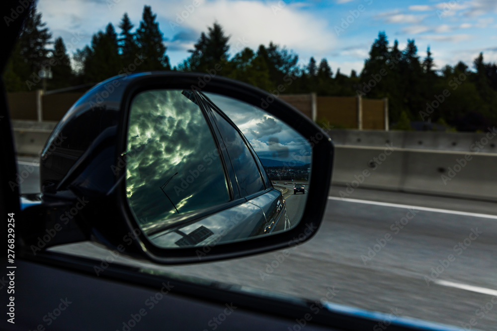 Dramatic cloud in reflection in side view mirror of car