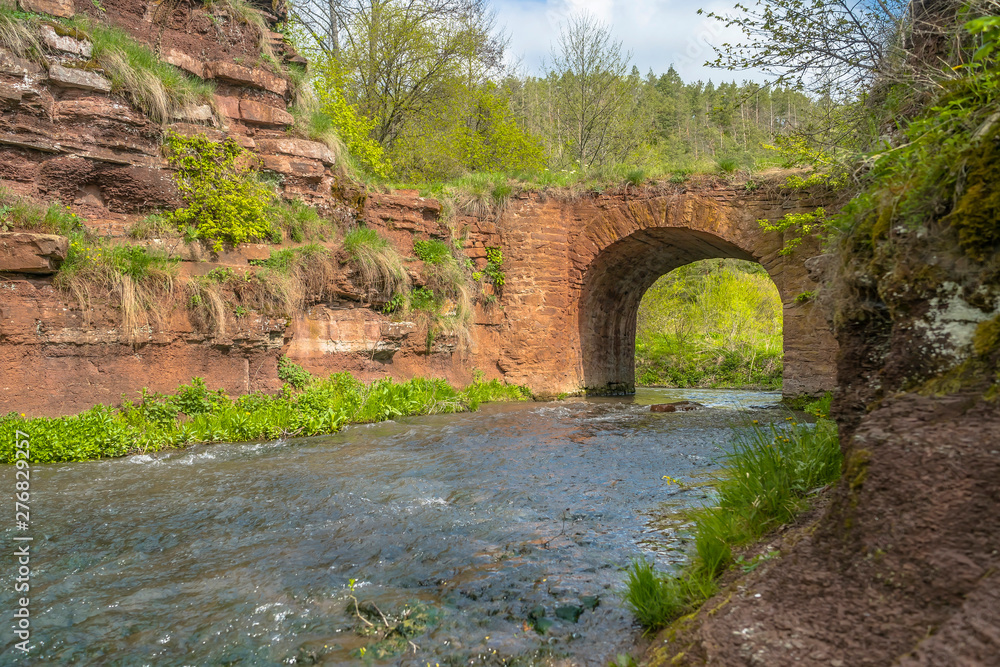 Mountain river flowing through stone bridge arch
