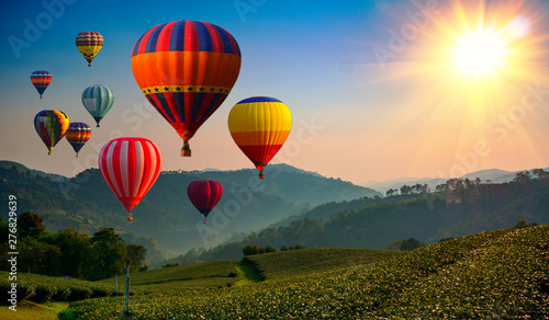 Hot air balloon above high mountain at sunrise or sunset.