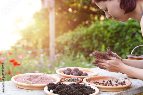 woman is manufacturing seed balls or seed bombs on a wooden table photo