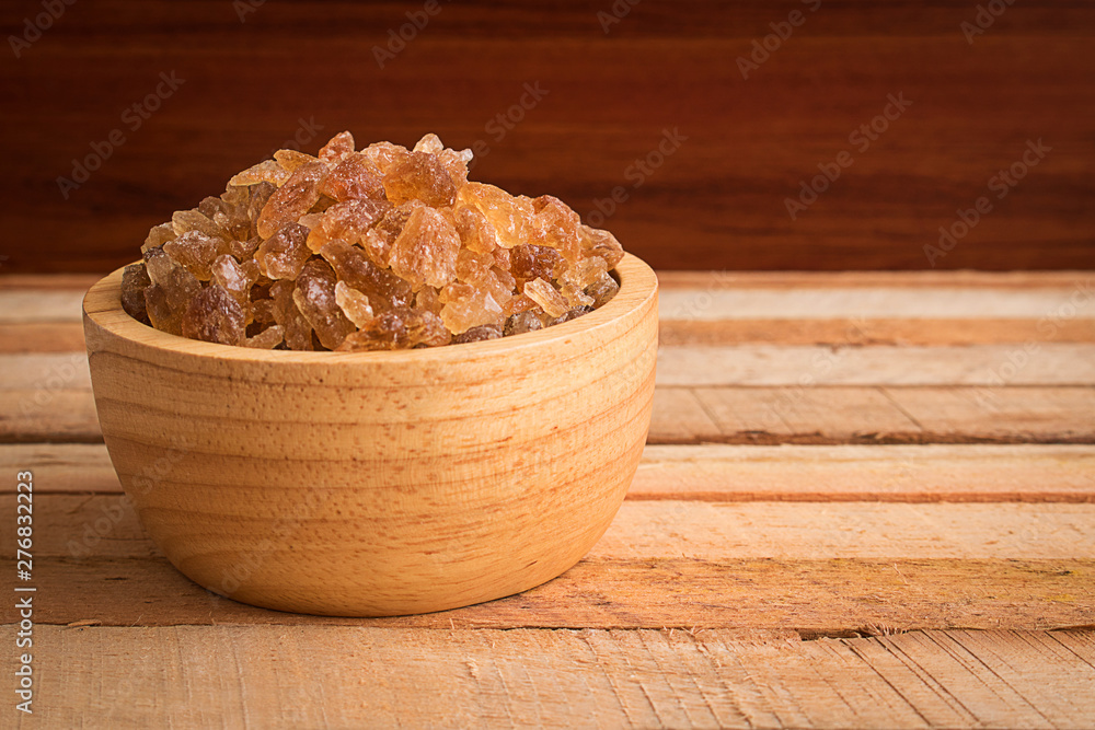 Natural rock sugar in wooden bowl on rustic table Natural rock sugar in wooden bowl on rustic table