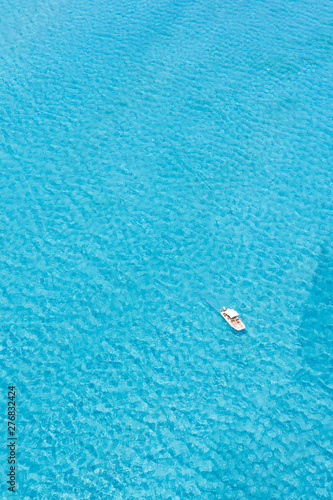View from above, stunning aerial view of an inflatable boat with tourists on board sailing on a beautiful turquoise clear water. Spiaggia La Pelosa (Pelosa beach) Stintino, Sardinia, Italy.