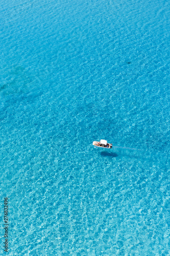 View from above, stunning aerial view of an inflatable boat with tourists on board sailing on a beautiful turquoise clear water. Spiaggia La Pelosa (Pelosa beach) Stintino, Sardinia, Italy. © Travel Wild