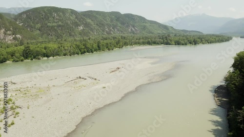 An aerial, cinematic, moving view of Skeena River shot in Terrace, B.C. Canada during the summer months on a sunny day. photo