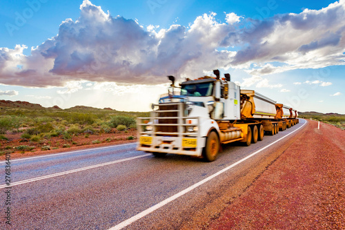 Intentionally blurred (in motion) road train with unbranded carriages on Australian outback highway. Pilbara mining region, Western Australia.