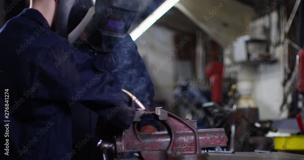 4K Young apprentice getting trained on the job in metalwork factory. Slow motion. 4K Young apprentice getting trained on the job in metalwork factory. Slow motion.