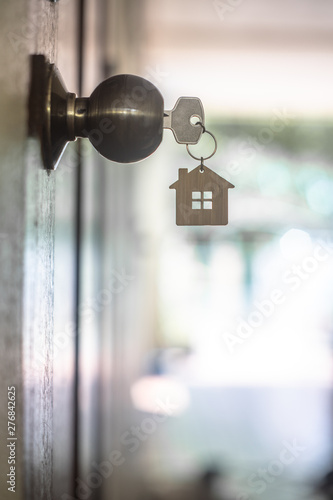 House key with home keyring in keyhole on wood door