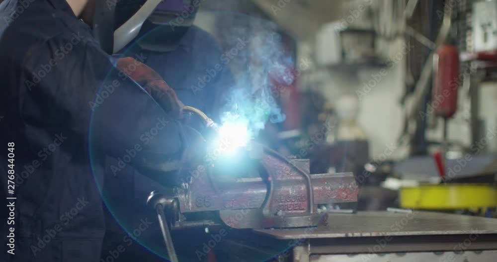 4K Young industrial worker in metalwork factory being supervised by smiling senior worker. Slow motion. 4K Young industrial worker in metalwork factory being supervised by smiling senior worker. Slow motion.