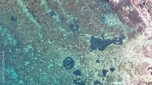 Overhead drone footage of transparent azure waters on the rocky shores of Sicily near Sferracavallo village, Palermo province, Italy. photo