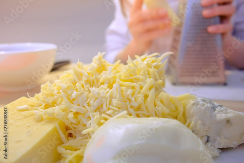 Woman rubs cheese on grater at home in the kitchen, hands close-up photo