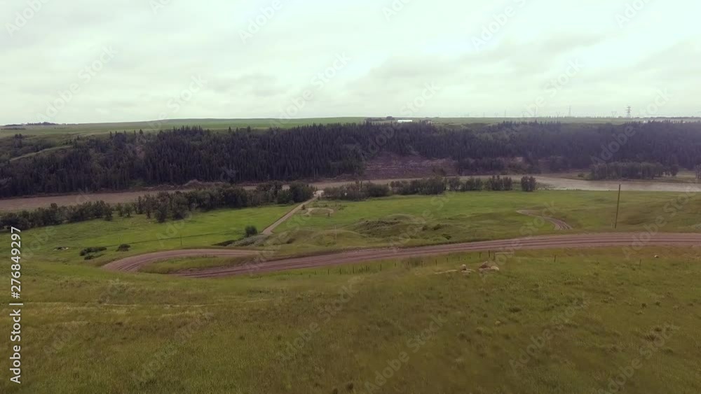 A circuitous dirt road leads into a beautiful prairie river valley A circuitous dirt road leads into a beautiful prairie river valley