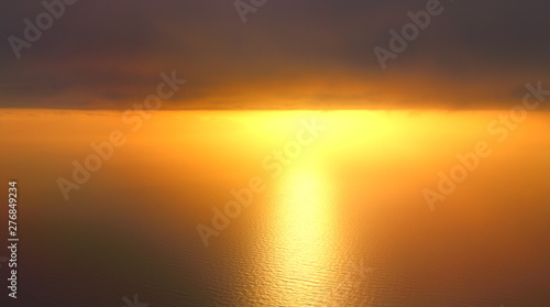 evocative imagine of sunset over the sea from the plane with clouds in the background