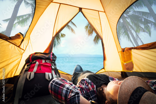 Hipster woman resting and sleeping in the tent picnic on holiday with the beautiful sea view background , travel and journey happy time concept.