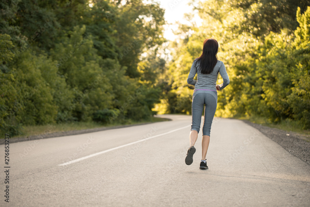 girl on a morning run. girl runs on the road. woman sport