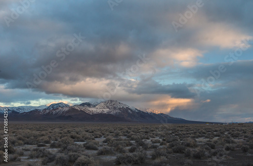 Storm clouds above mountains with cars traveling in the distance