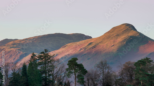 Beautiful landscape image of Catbells in Lake District hit by first light during Autumn Fall sunrise viewed from Derwent Water at Keswick