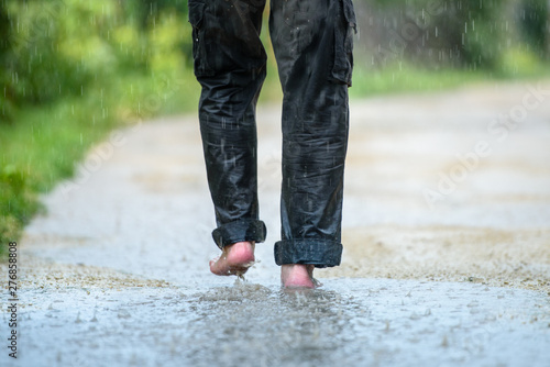 A man in the rain is barefoot in puddles
