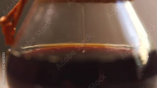 Dripping coffee into container looking at the bottom of a glass container when you see a stream of coffee dripping through a white natural filter on the bottom press capture in slow motion at 120 FPS.